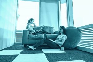 Zwei junge Frauen lesen vor einem Fenster